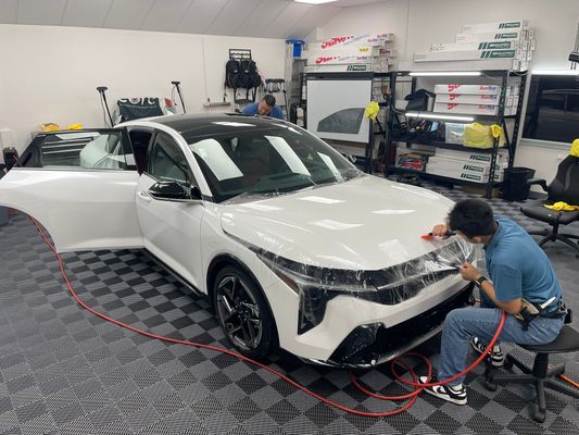 Technician applying paint protection film to a white vehicle