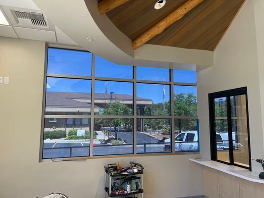 Office lobby with tinted floor-to-ceiling windows and wood beam ceiling
