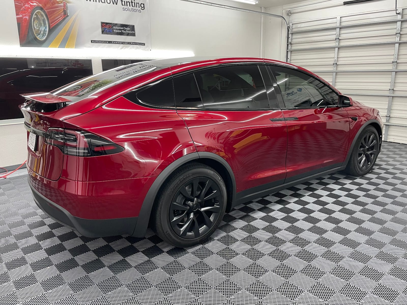 Red Tesla Model X on the checkered floor inside the Pacific Window Tint shop