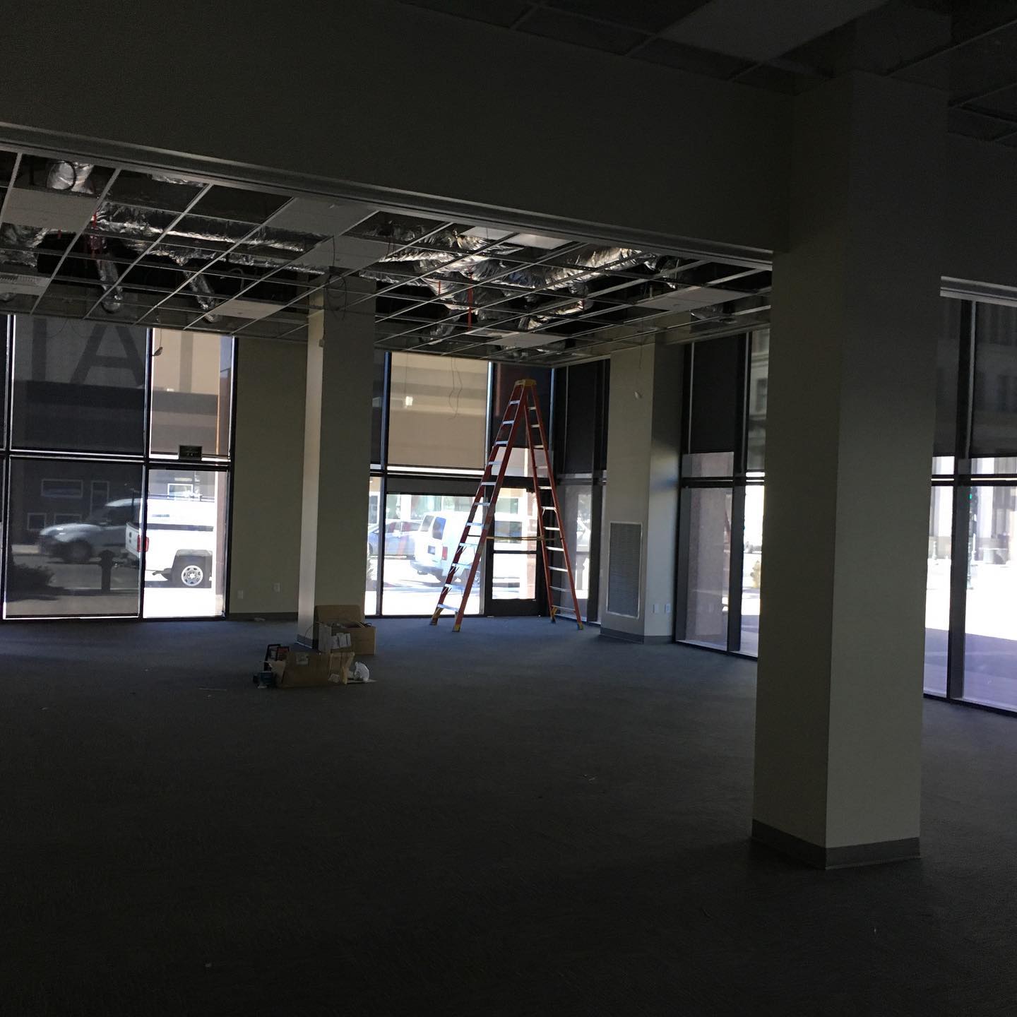 Empty commercial space with a wall of windows and a ladder