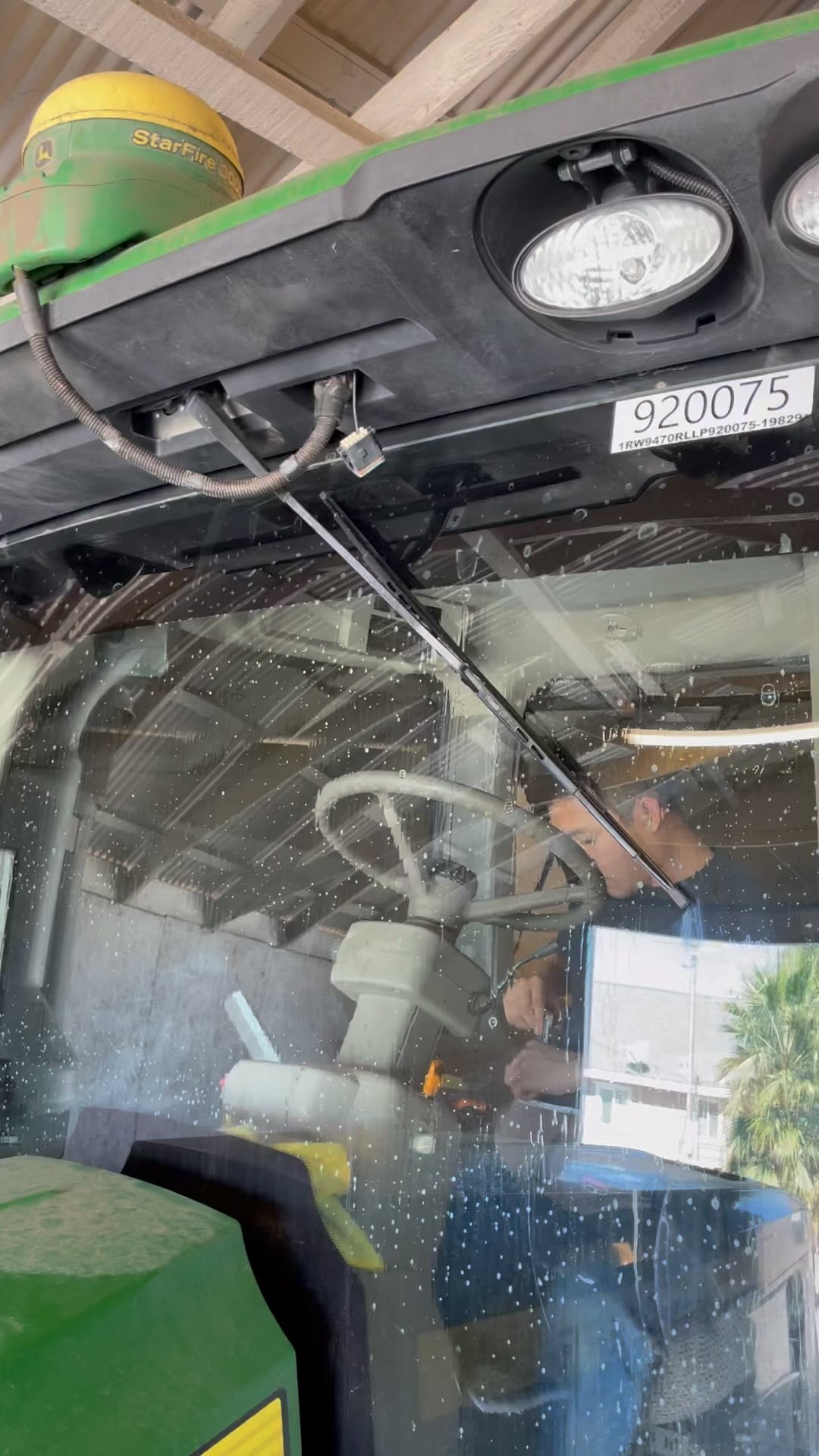 Inside a tractor cab, looking out through the tinted windshield