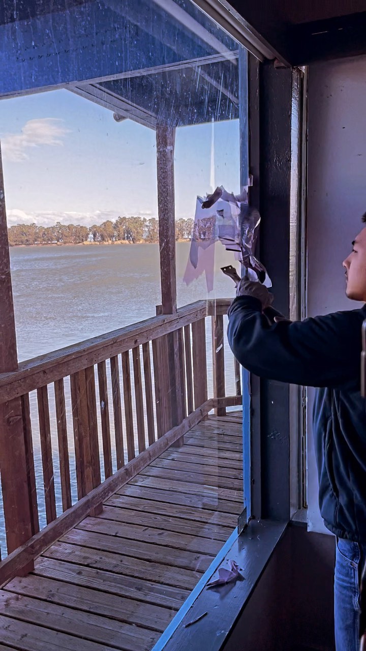 Installer removing old tint from a lakeside restaurant door