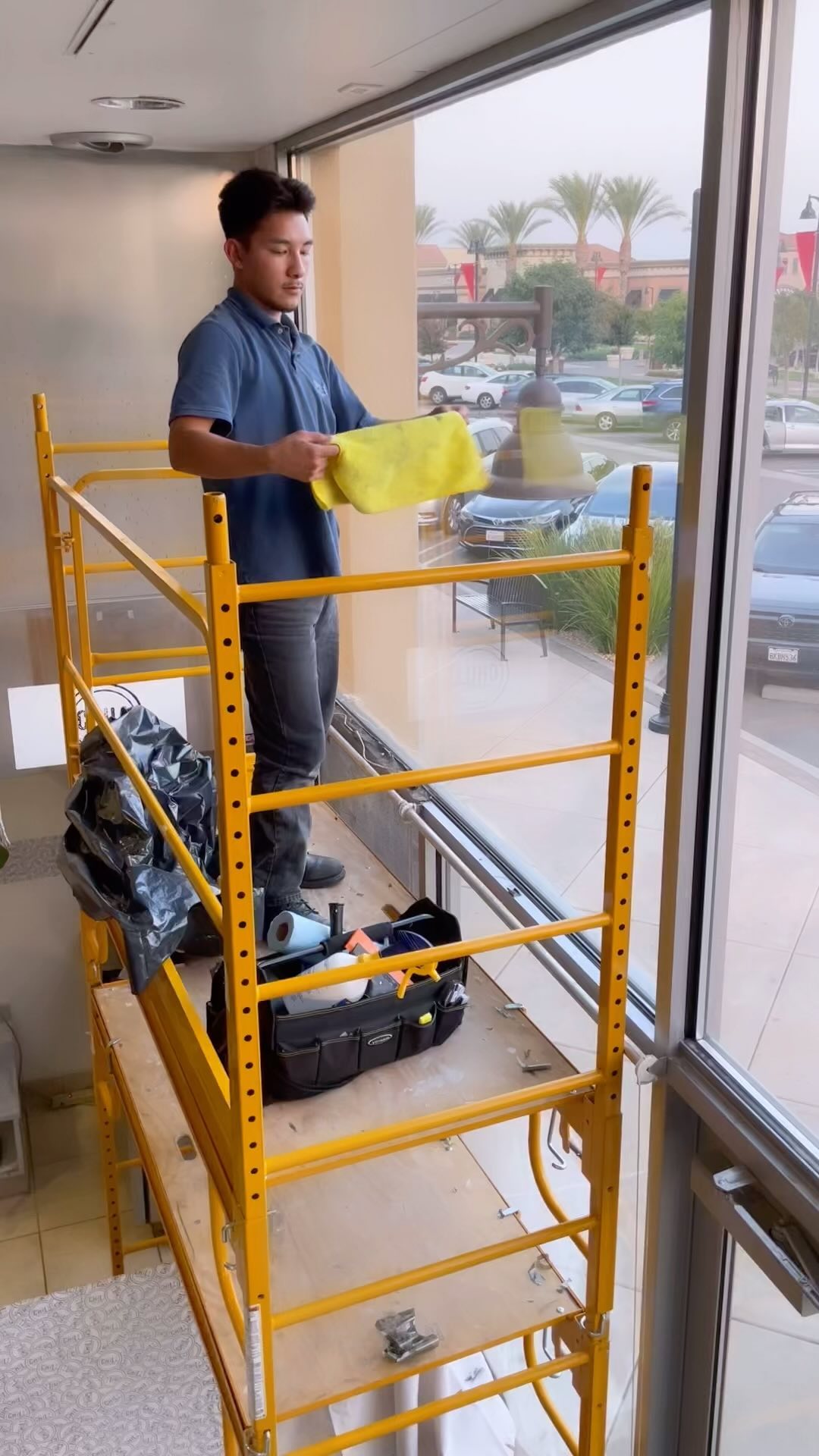 Installer on a scaffold tinting tall storefront windows